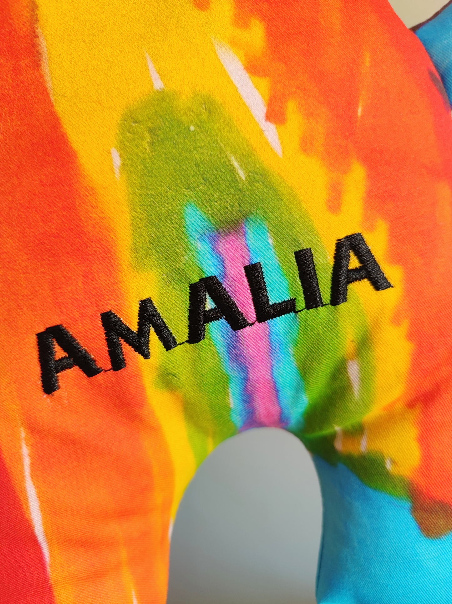 il ricamo del nome Amalia scritto in nero realizzato su di un pupazzo monamì color arcobaleno